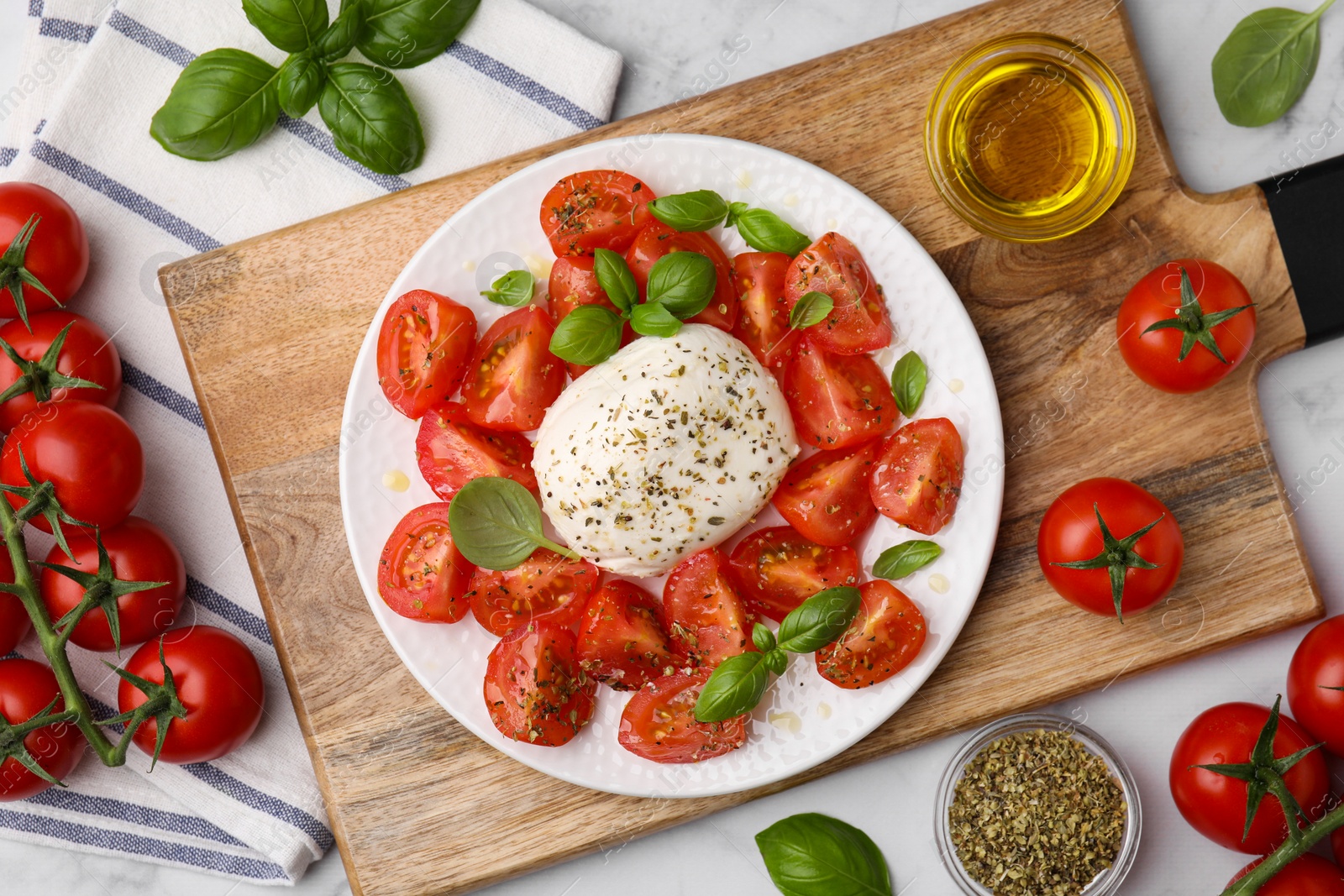 Photo of Tasty salad Caprese with mozarella, tomatoes, basil and other ingredients on light table, flat lay