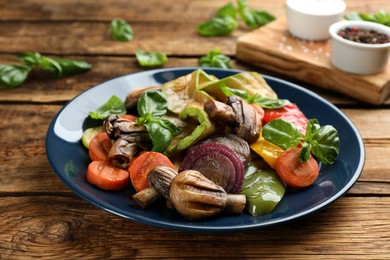 Photo of Delicious grilled vegetables with basil on wooden table