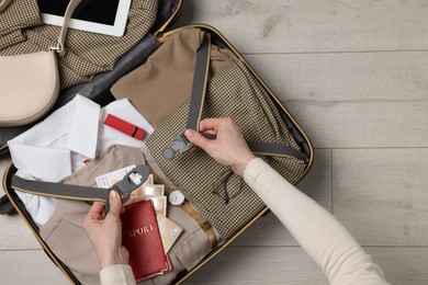 Photo of Woman packing suitcase on wooden floor, top view with space for text. Business trip planning