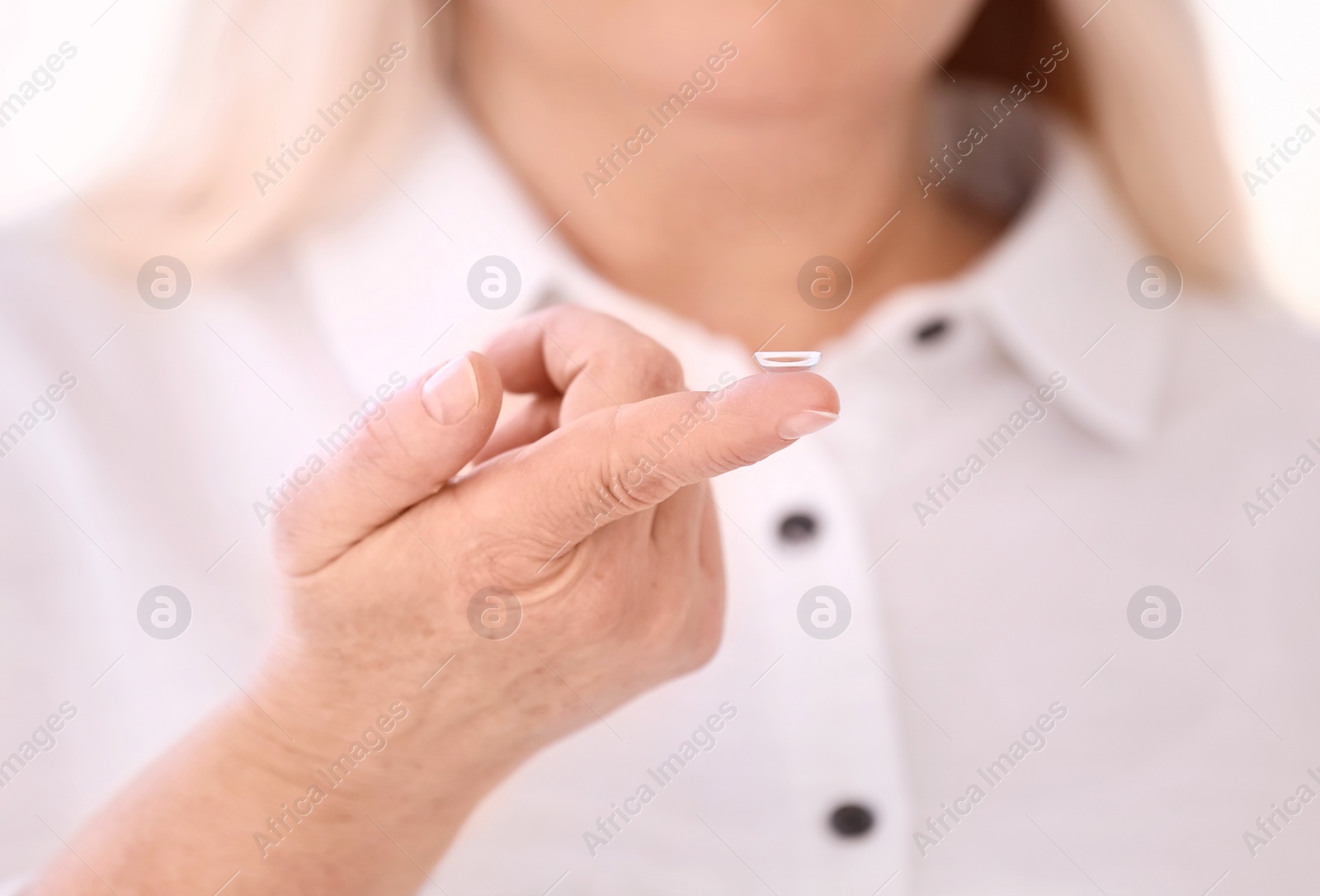 Photo of Senior woman with contact lens on light background