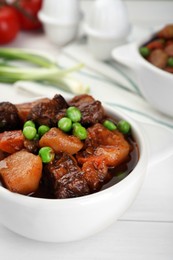 Photo of Delicious beef stew with carrots, peas and potatoes on white wooden table, closeup