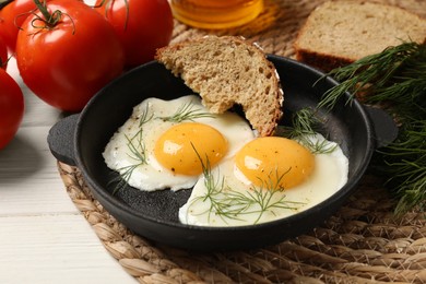 Delicious fried eggs served with bread on white wooden table, closeup