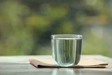Glass of pure water on wooden table, space for text