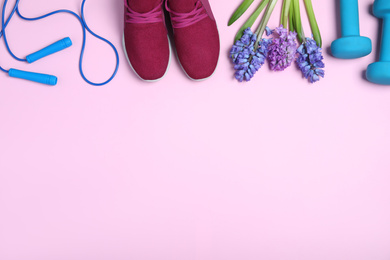 Photo of Flat lay composition with spring flowers and sports items on pink background. Space for text