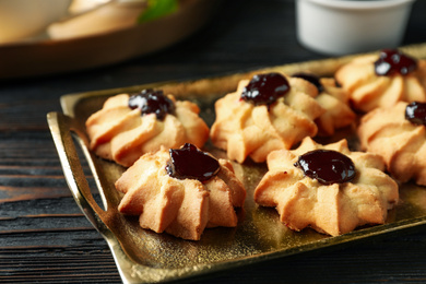 Tasty shortbread cookies with jam on black wooden table, closeup