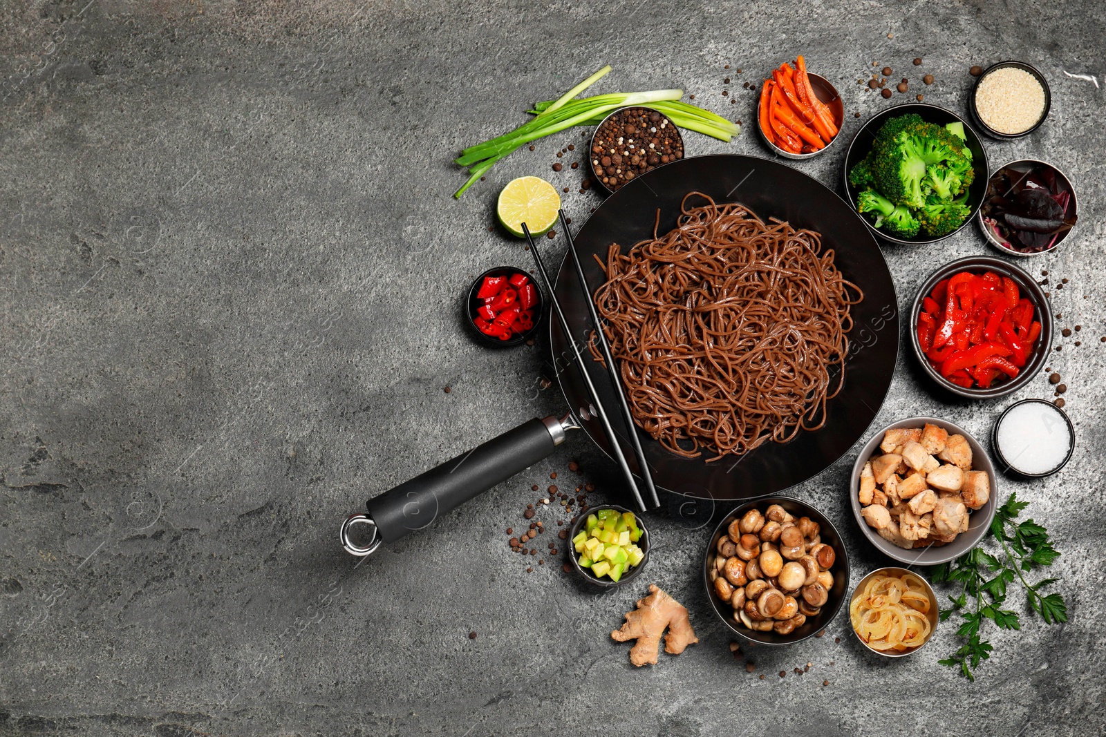 Photo of Wok with noodles, chicken and other products on grey table, flat lay. Space for text