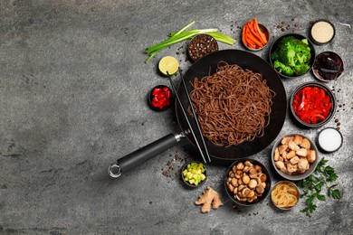 Photo of Wok with noodles, chicken and other products on grey table, flat lay. Space for text