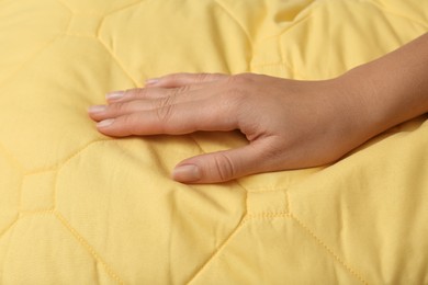 Photo of Woman touching soft yellow pillow, closeup of hand