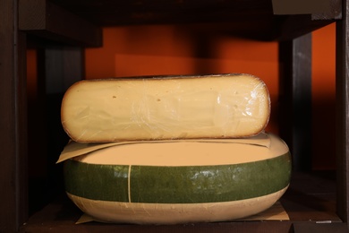 Photo of Delicious cheese on rack shelf in store. Dairy product