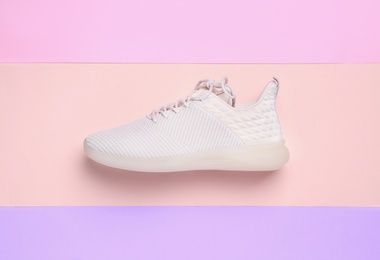 Stylish sporty sneaker on color background, top view