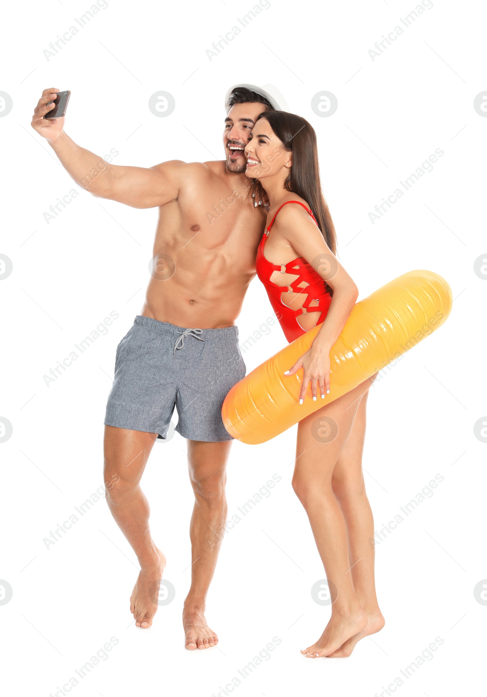 Photo of Young attractive couple in beachwear with inflatable ring taking selfie on white background