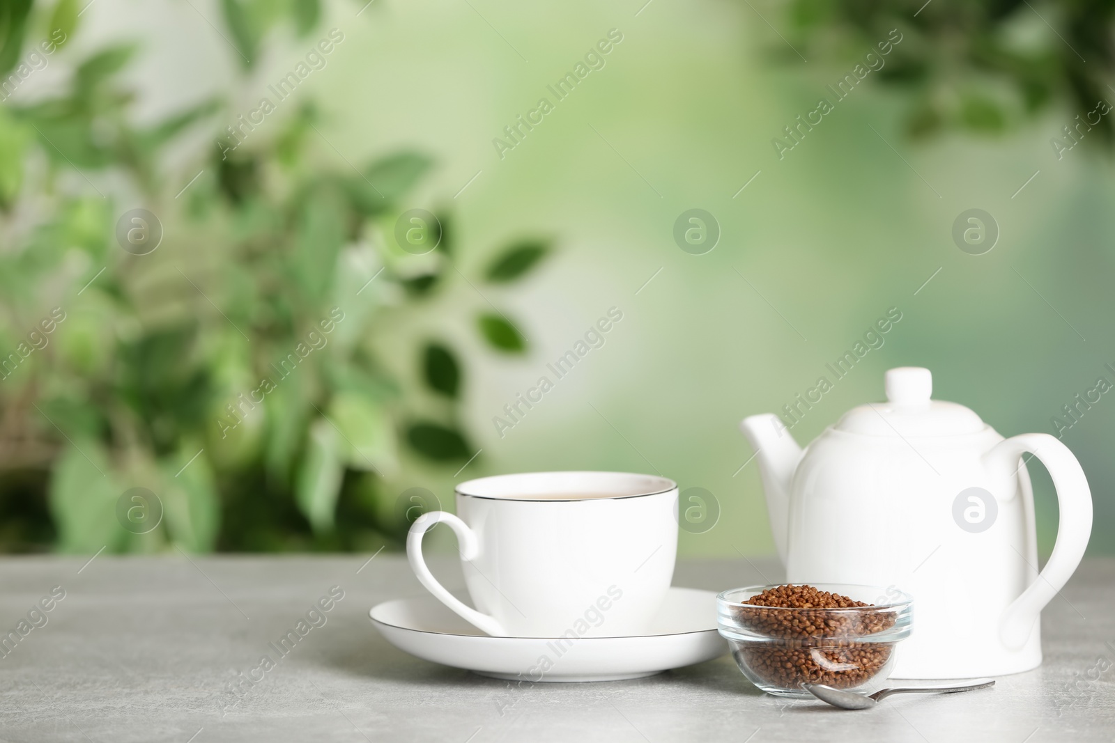 Photo of Buckwheat tea and granules on table against blurred background. Space for text