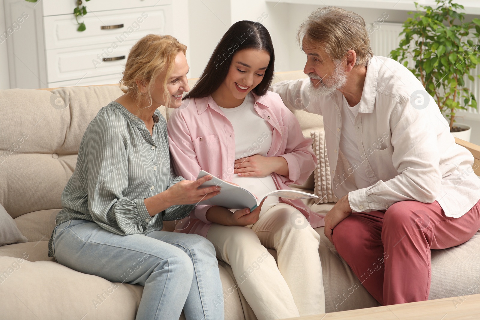 Photo of Happy pregnant woman spending time with her parents at home. Grandparents' reaction to future grandson