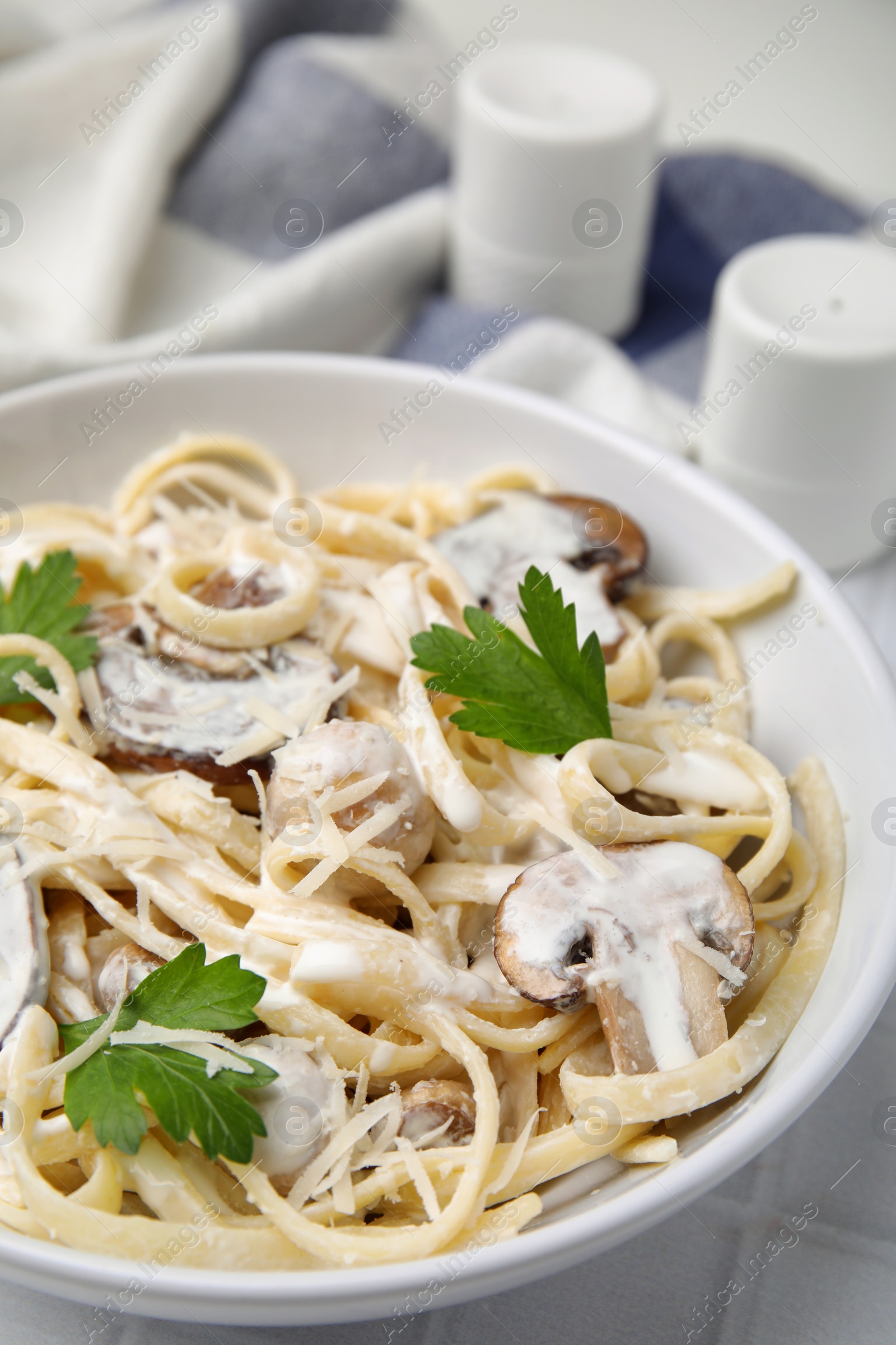 Photo of Delicious pasta with mushrooms on white tiled table, closeup