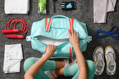 Photo of Woman with bag and sports items on grey carpet, top view
