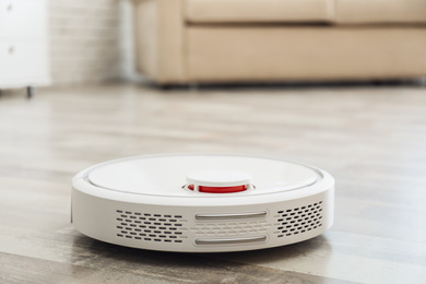 Photo of Modern robotic vacuum cleaner on floor in living room. Space for text