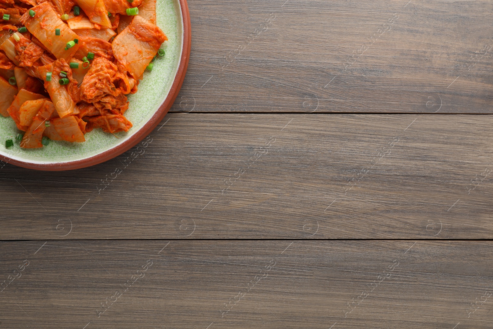 Photo of Plate of delicious kimchi with Chinese cabbage on wooden table, top view. Space for text