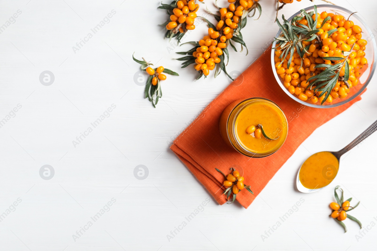 Photo of Delicious sea buckthorn jam and fresh berries on white wooden table, flat lay. Space for text