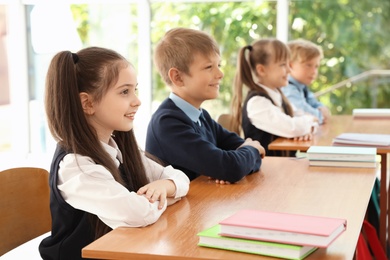 Photo of Little children in classroom. Stylish school uniform