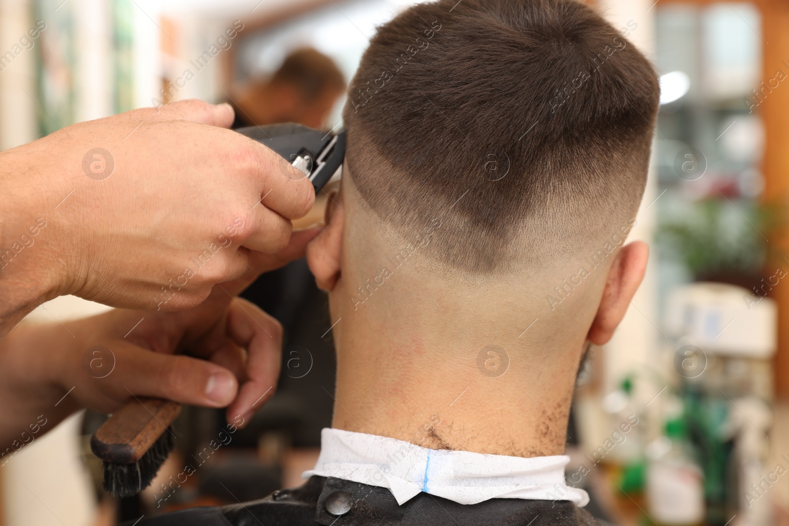 Photo of Professional hairdresser working with client in barbershop, closeup