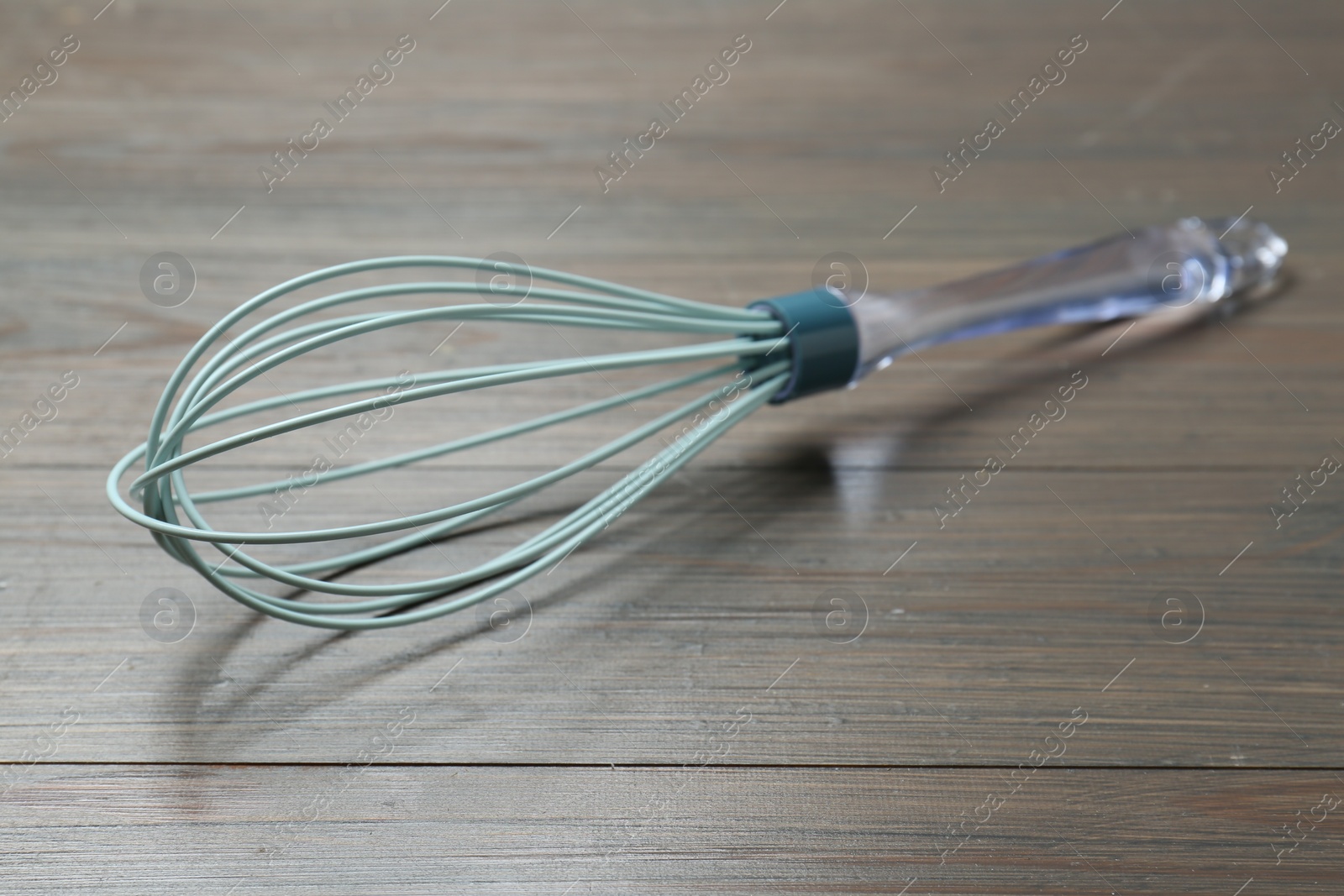 Photo of One whisk on wooden table, closeup. Kitchen tool