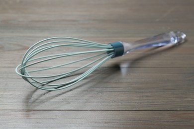 Photo of One whisk on wooden table, closeup. Kitchen tool