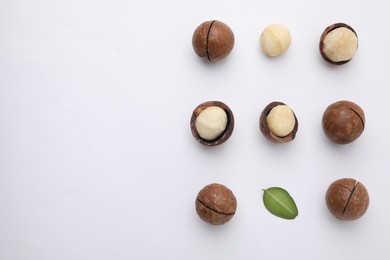 Tasty Macadamia nuts and green leaf on white background, flat lay. Space for text