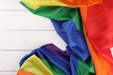 Rainbow LGBT flag on white wooden table, top view
