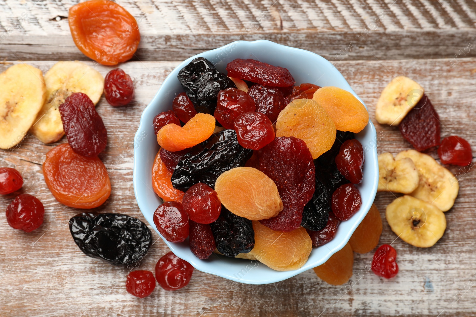 Photo of Mix of delicious dried fruits on wooden table, flat lay