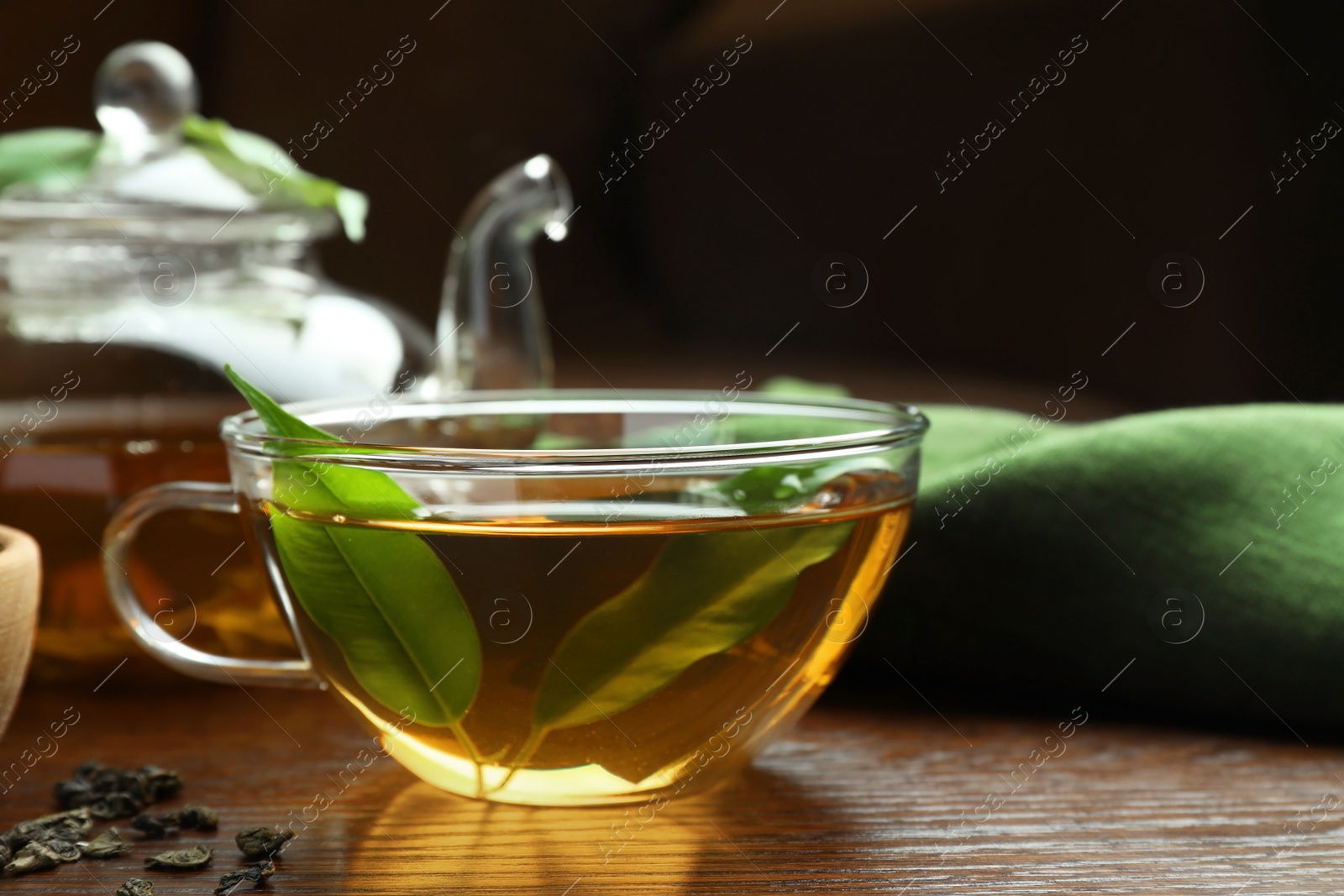Photo of Fresh green tea in glass cup with leaves on wooden table