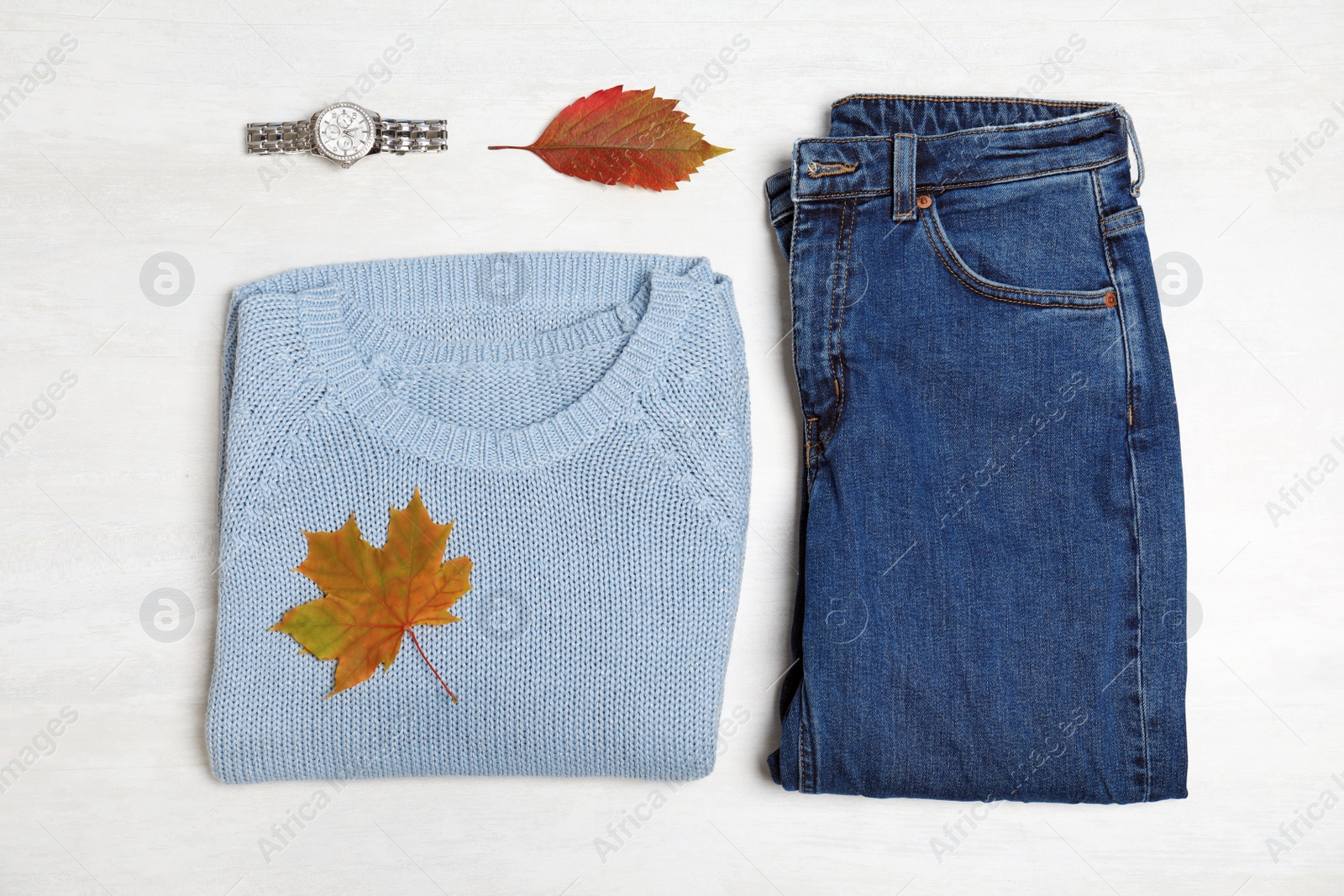 Photo of Stylish outfit and autumn leaves on white wooden background, flat lay. Trendy warm clothes