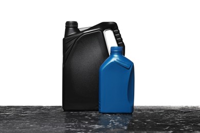 Photo of Motor oil in different canisters on black table against white background