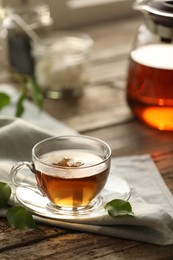 Photo of Tasty tea in cup on wooden table, closeup