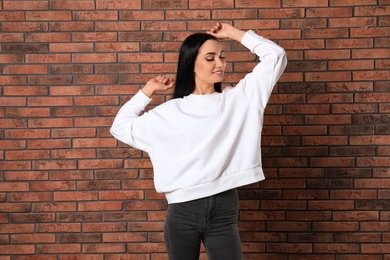 Photo of Portrait of young woman in sweater at brick wall. Mock up for design