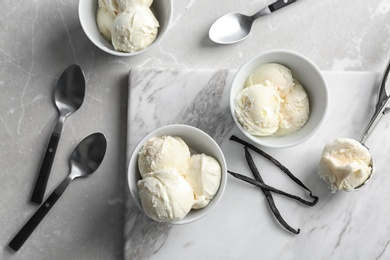 Photo of Bowls with tasty vanilla ice cream on marble board