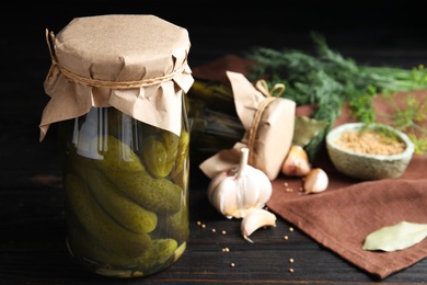 Jars with pickled cucumbers on black wooden table