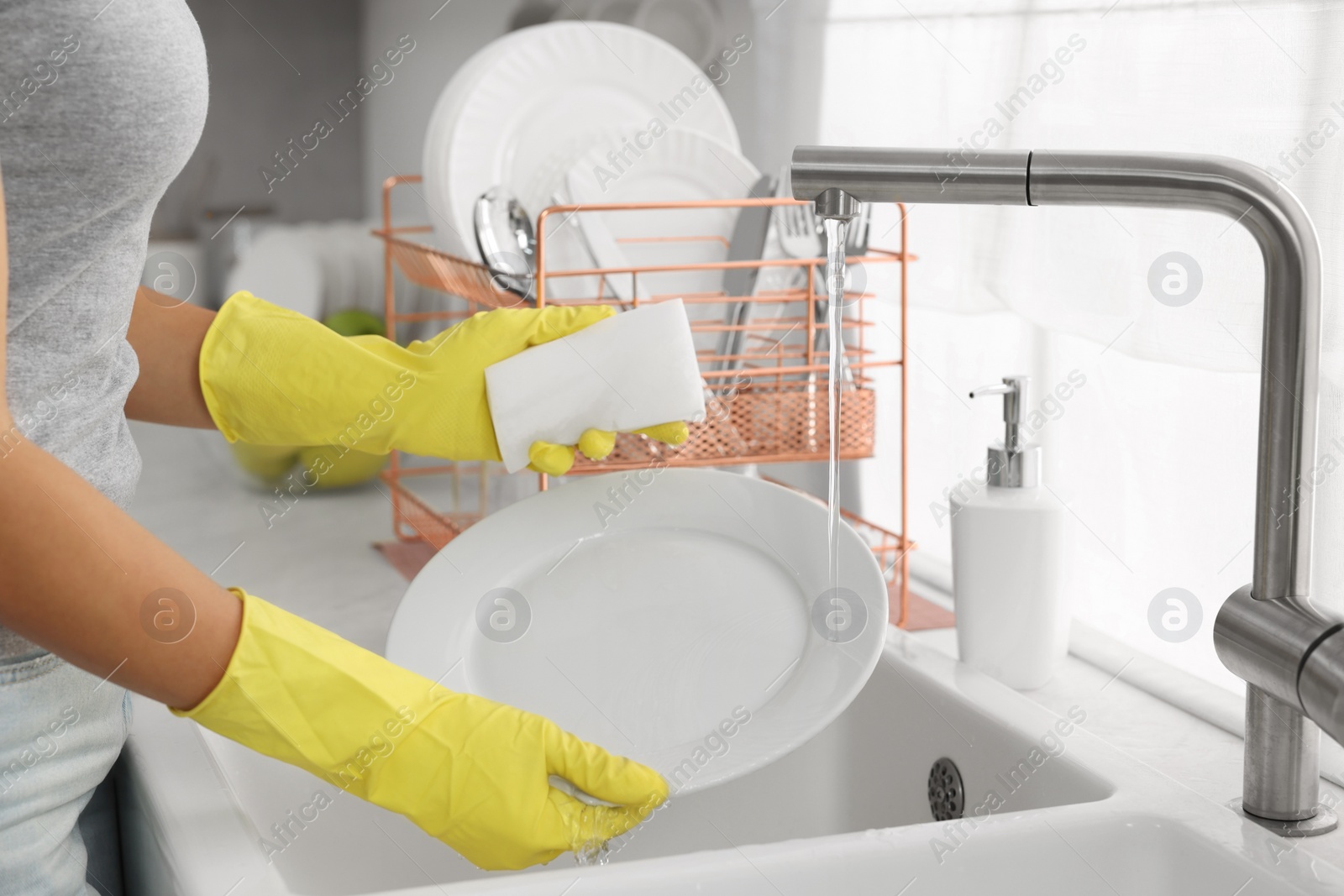 Photo of Woman washing plate at sink in kitchen, closeup