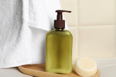 Photo of Shampoo bottle, towel and solid shampoo bar on white table