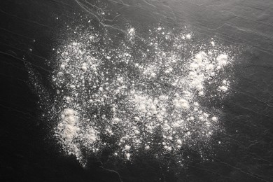 Photo of Scattered flour on black textured table, top view