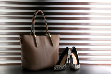 Stylish woman's bag and shoes on dark grey table
