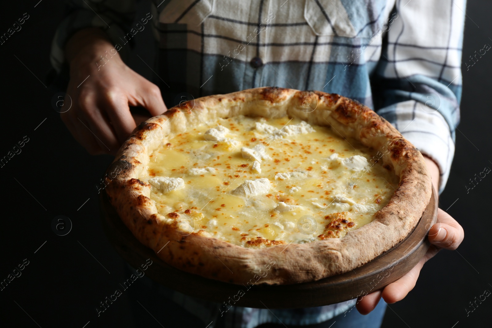 Photo of Woman holding delicious cheese pizza on black background, closeup