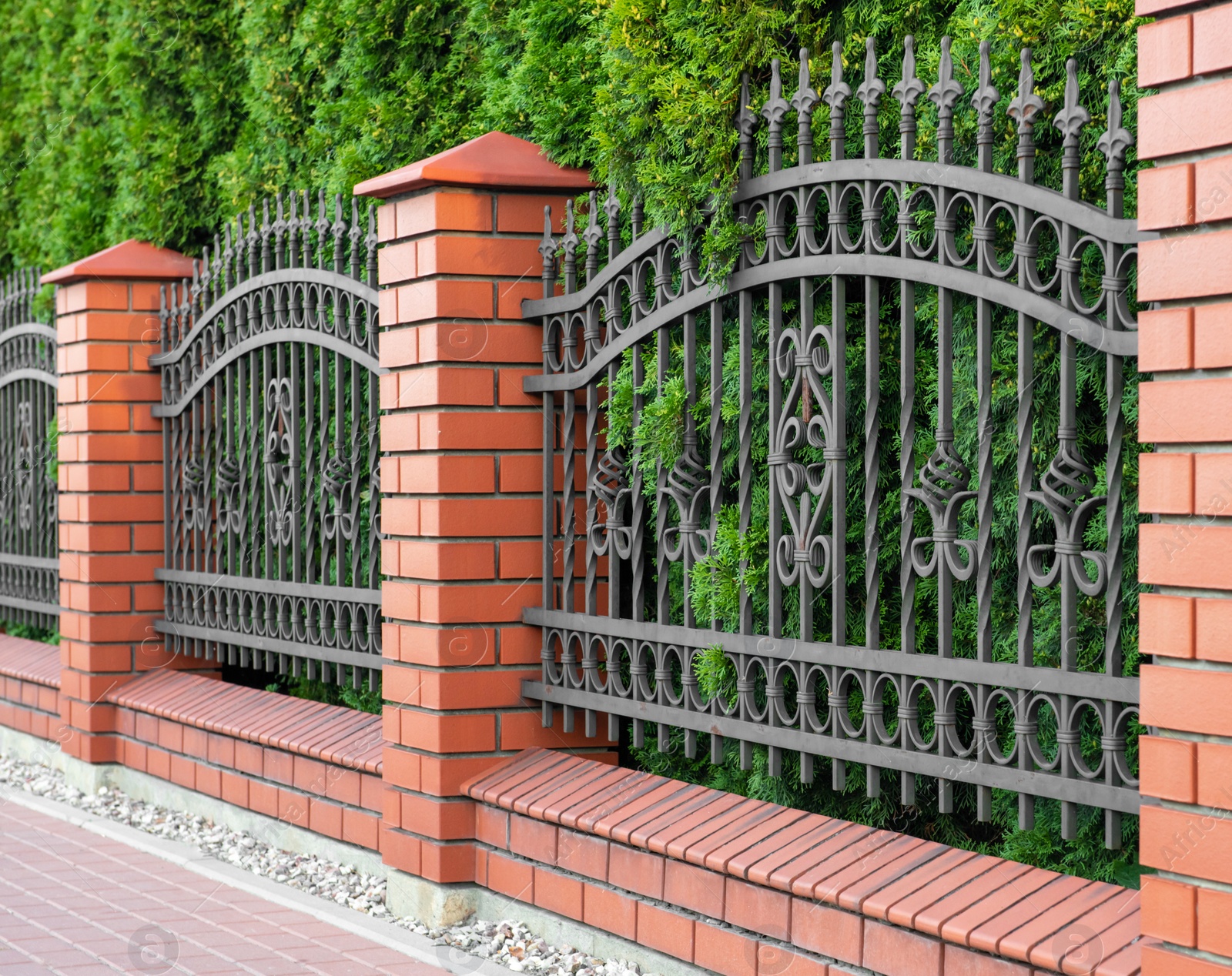 Photo of Beautiful brick fence with iron railing outdoors