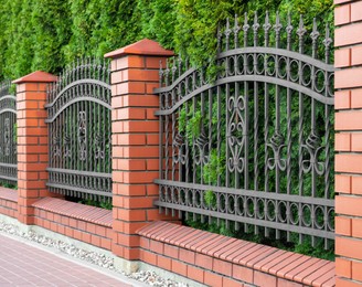 Beautiful brick fence with iron railing outdoors