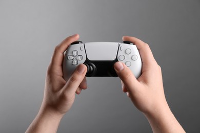 Photo of Woman using wireless game controller on grey background, closeup