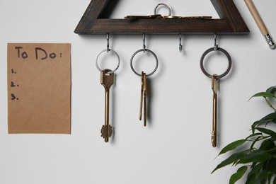Photo of Wooden key holder and to do list on light grey wall indoors