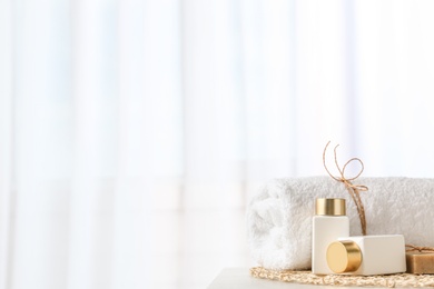 Photo of Cosmetic bottles and towel on light grey table indoors, space for text. Spa treatment