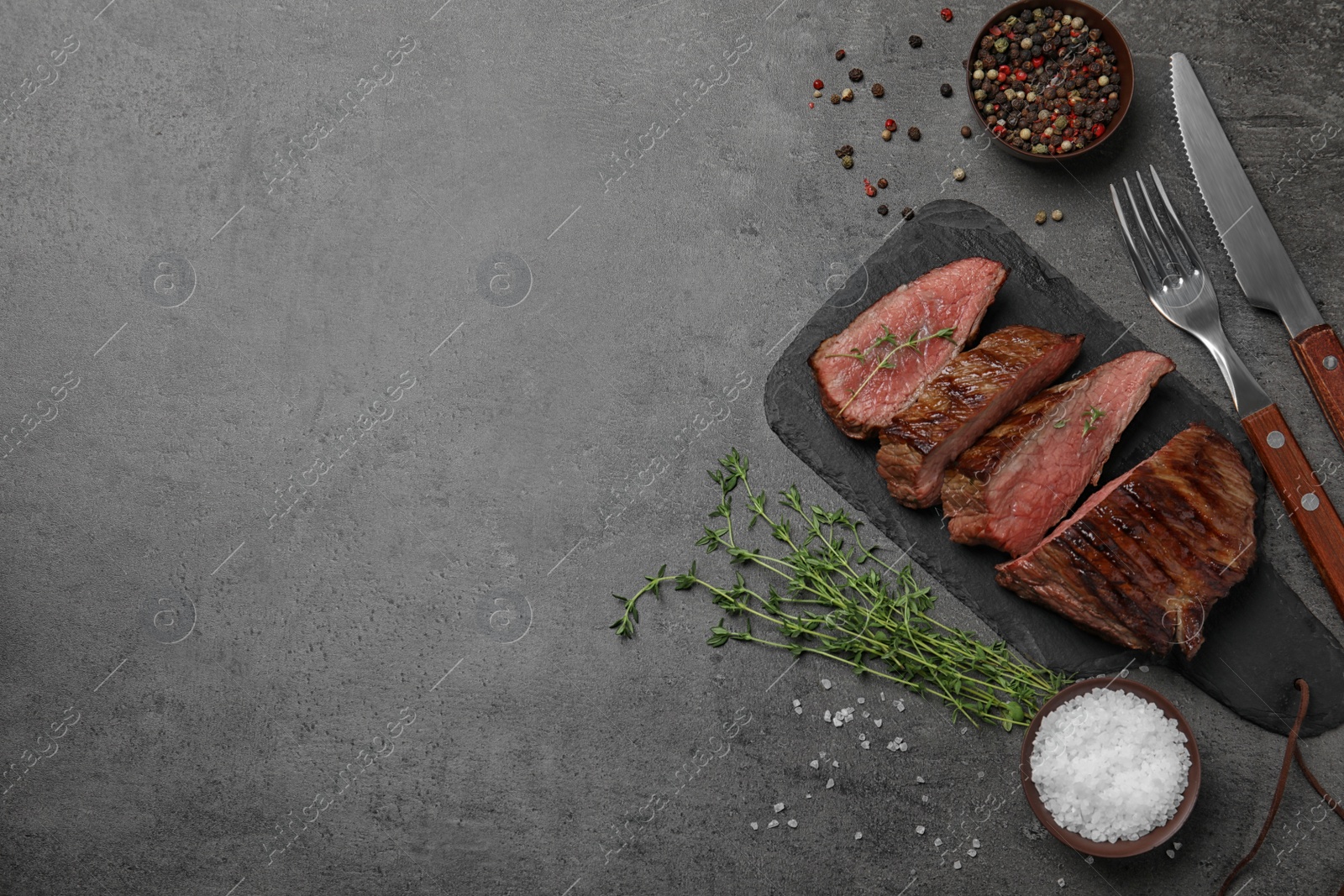 Photo of Flat lay composition with slices of grilled meat on grey table. Space for text