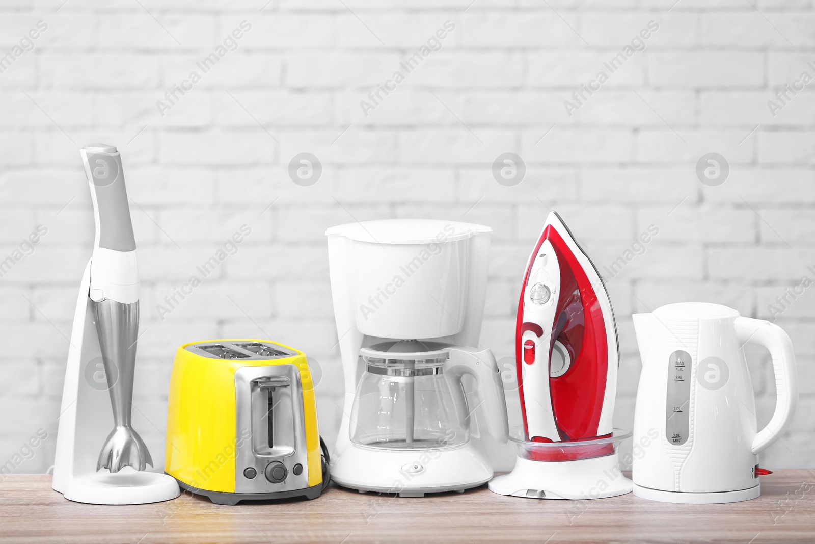 Photo of Household and kitchen appliances on table against brick wall background. Interior element