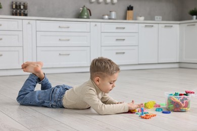 Photo of Cute little boy playing on warm floor in kitchen. Heating system