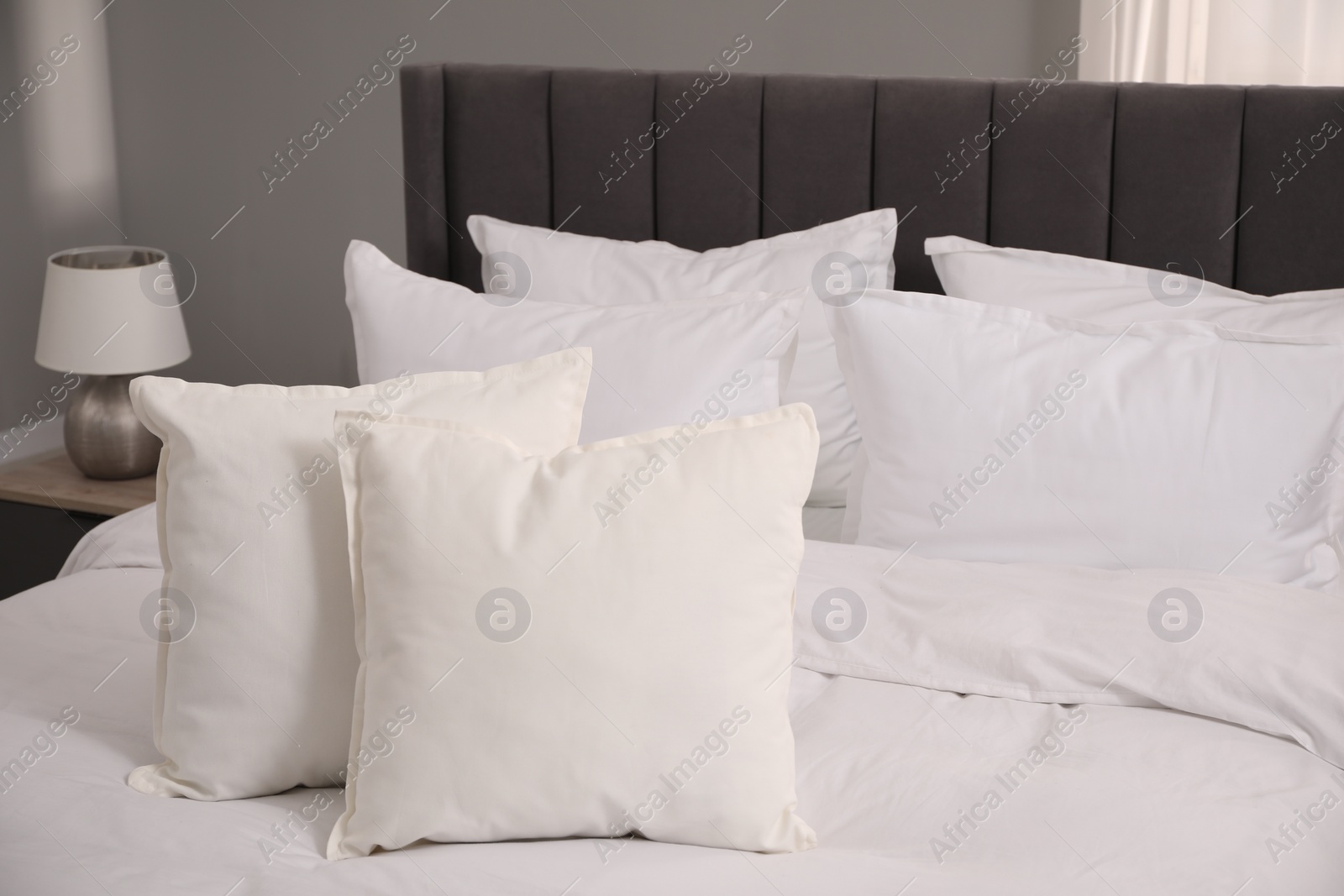 Photo of Many soft white pillows and duvet on bed indoors